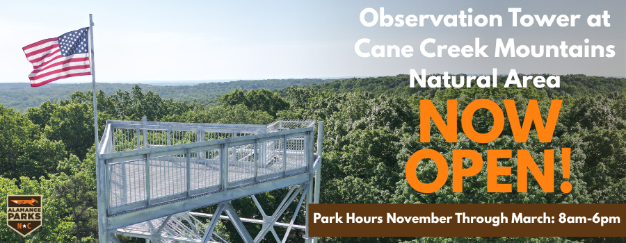 image of metal observation tower with an american flag overlooking the trees in cane creek mountains natural area and the skyline of alamance county