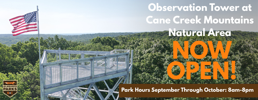 image of the top of a tower overlooking trees with text announcing park hours